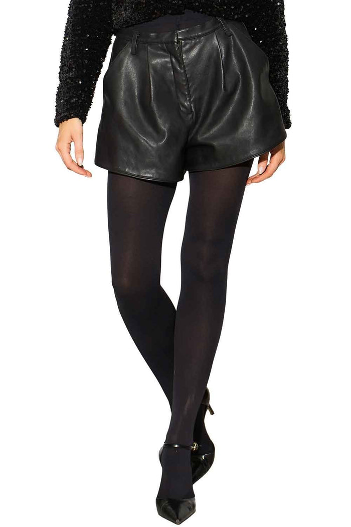 Model wearing black leather shorts and black opaque tights on a white background