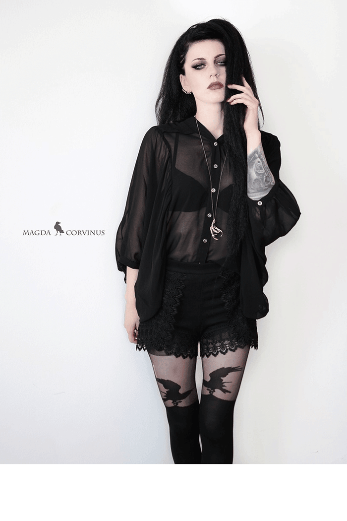 Person wearing a black outfit with over the knee patterned raven tights on a white background