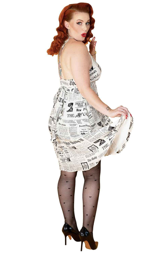 Woman wearing a dress made of newspaper and black all over heart tights on a white background