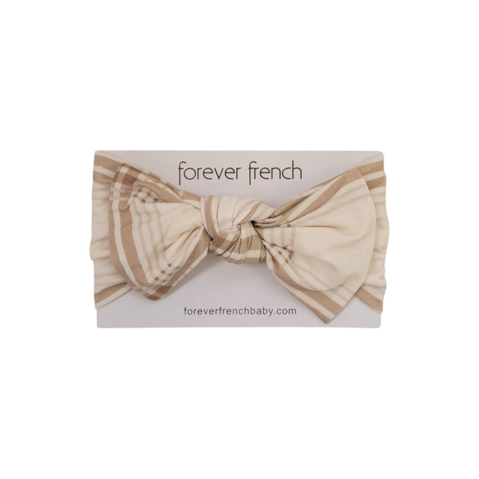 The Bamboo Head Wrap | Ellis Plaid by forever french baby features a cream and light brown plaid pattern with a large bow, displayed on branded packaging from forever french baby.