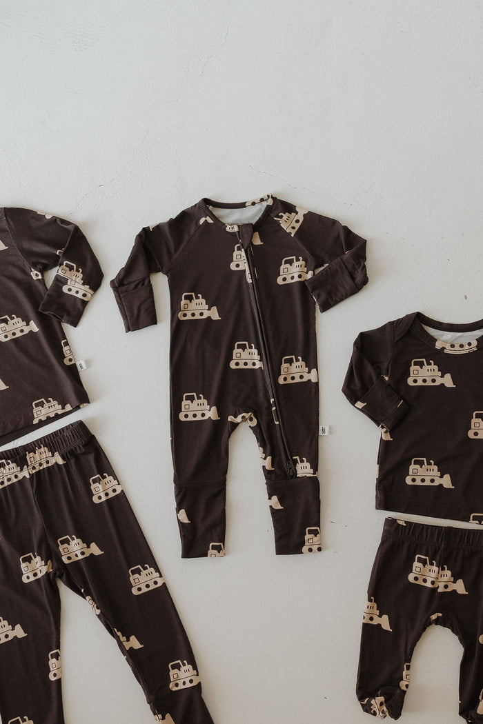 The Sleepy Time Set | Bulldozer by forever french baby includes four breathable bamboo pieces for children—a zip-up onesie, pants, long-sleeve shirt, and matching top—brown with beige bulldozers, displayed on a white surface.