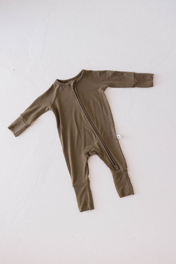 An Olive Green long-sleeve baby onesie from the Forever French Baby's FF Club collection, made of premium bamboo, is laid out on a white surface. It features a diagonal zipper running from the neck to the left ankle, fold-over cuffs on the sleeves, and a small fabric tag on the left side.