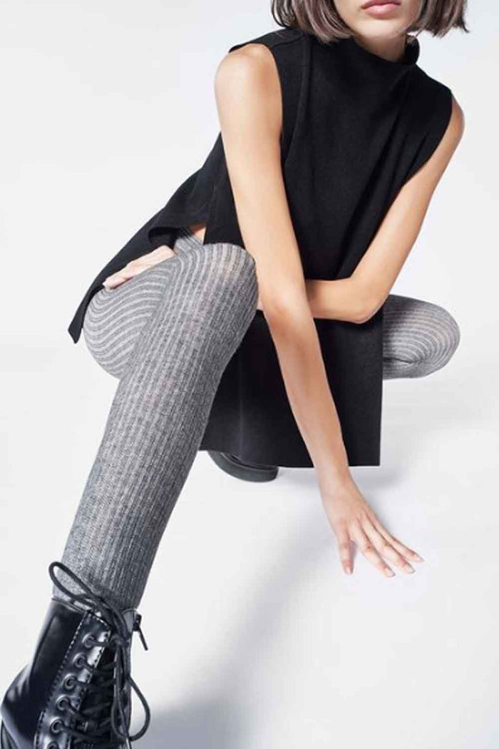 Person wearing a black sleeveless top and gray ribbed eco tights on a white background