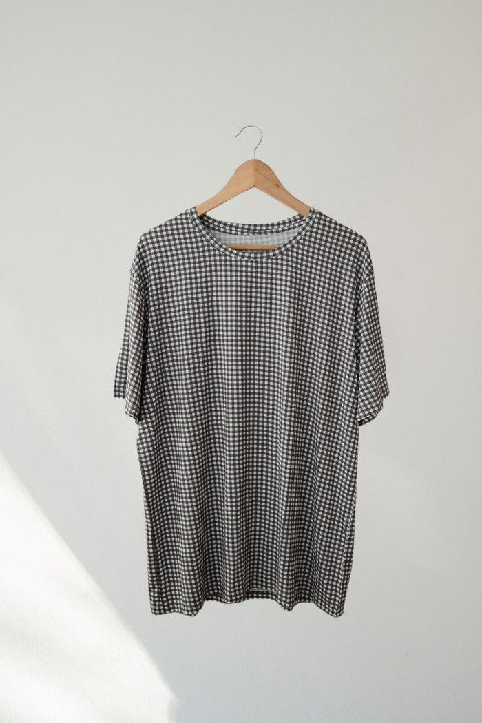 The Men's Short Sleeve Pajamas in Green Gingham by forever french baby, inspired by bamboo sleepwear, hang on a wooden hanger against a plain, light-colored wall.