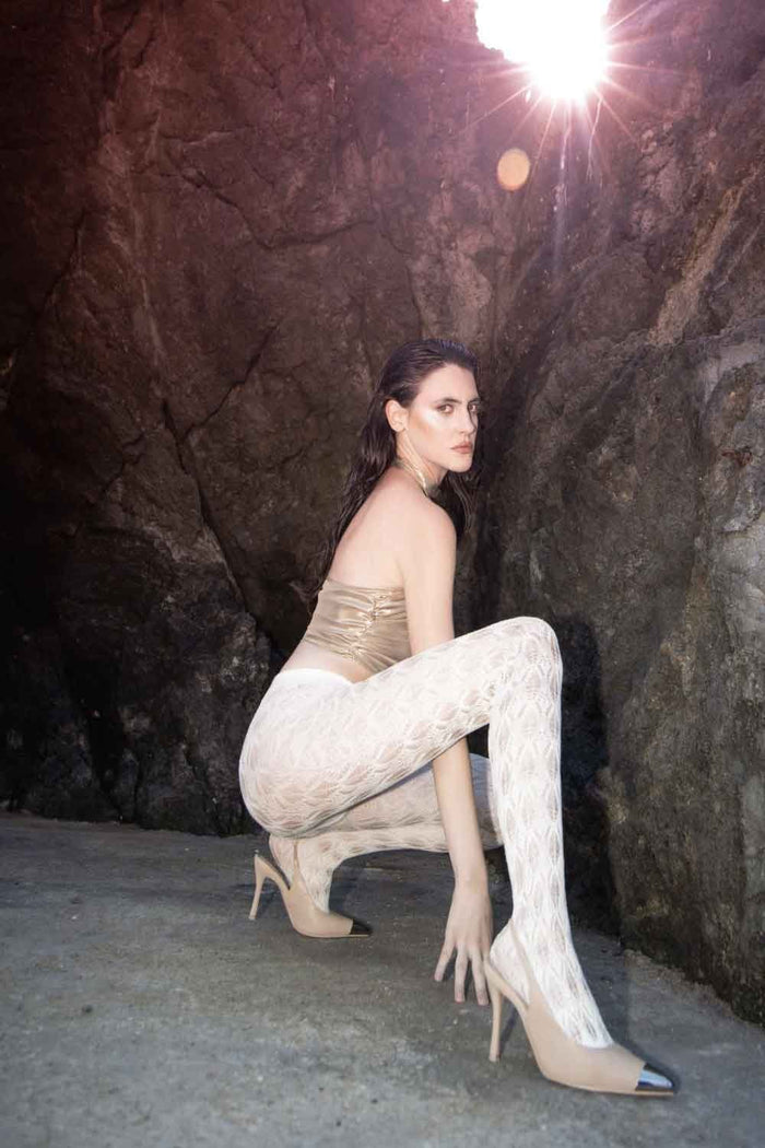 Woman wearing polaris white lace design tights posing against a rocky background