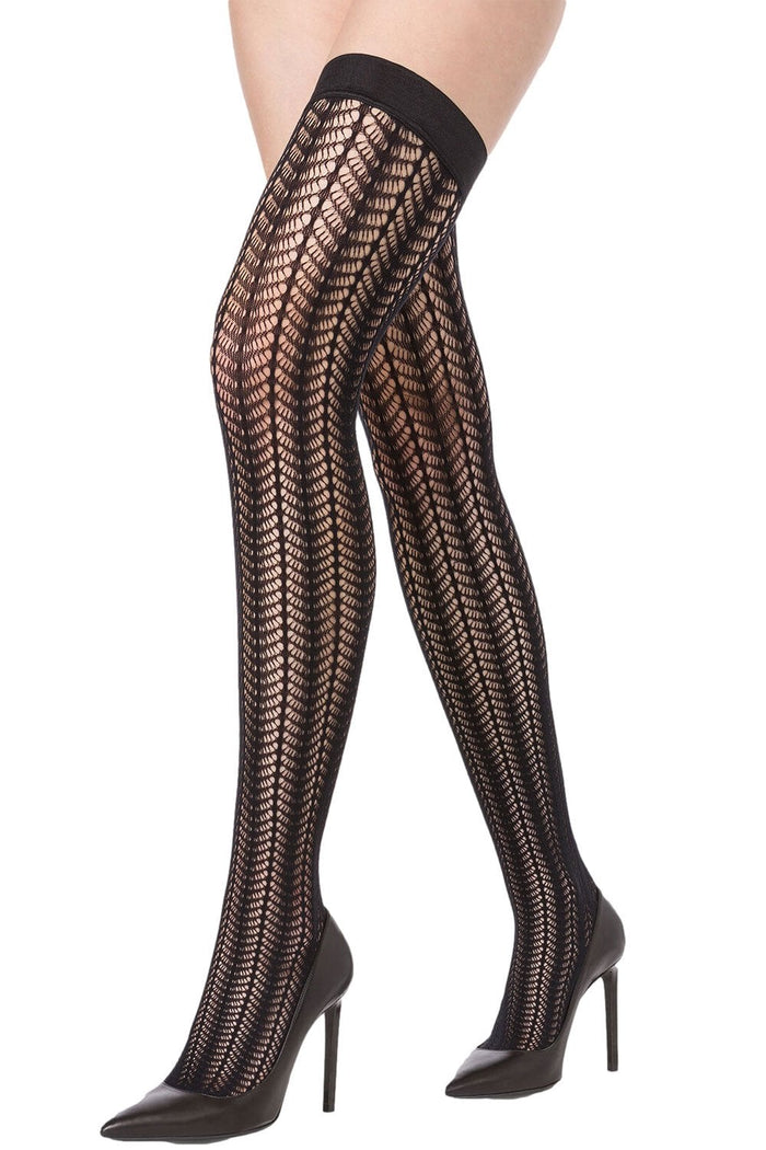 Black patterned net hold ups worn with black high heels on a white background