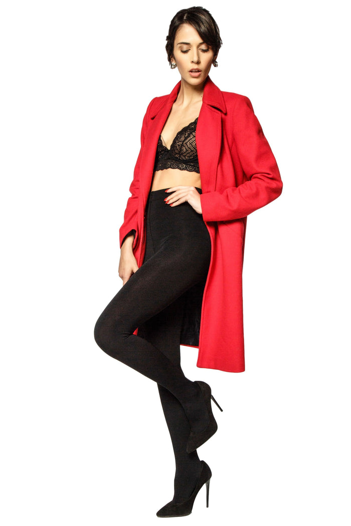 Woman wearing a red coat over a black outfit and black opaque tights on a white background