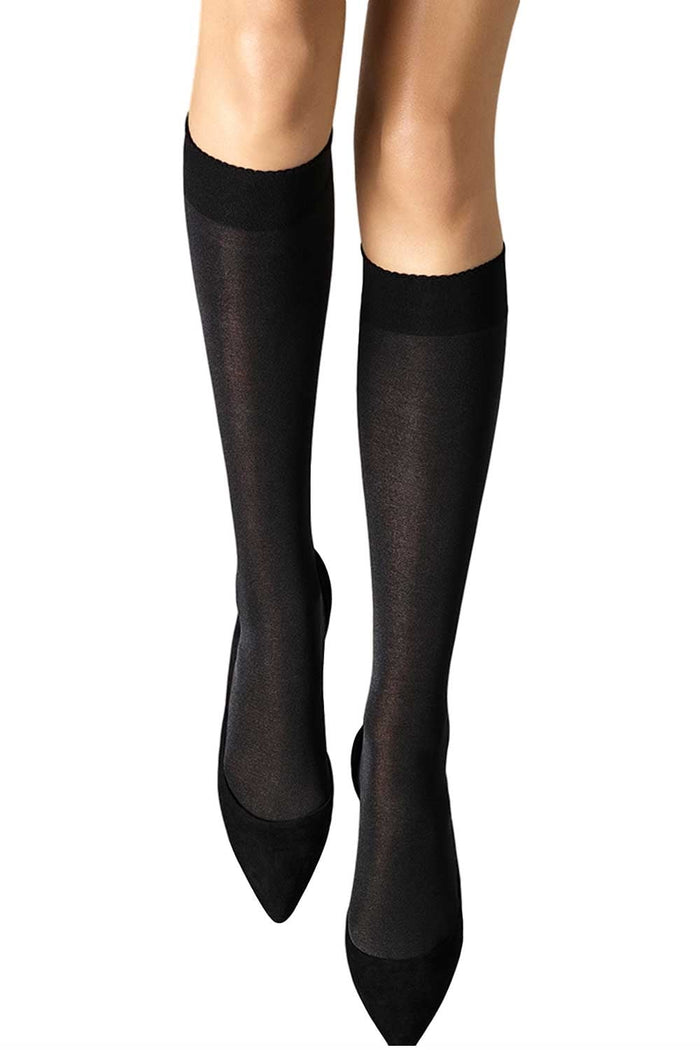 Black knee-high socks worn with black shoes on a white background