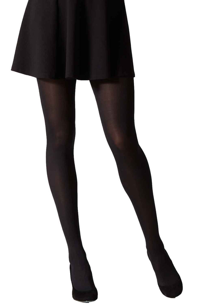 Model wearing black opaque tights and a black skirt on a white background