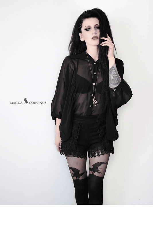 Person wearing a black outfit with over the knee patterned raven tights  on a white background