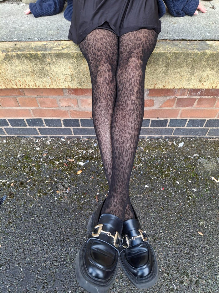 model wearing pretty polly animal print tights with black loafer shoes