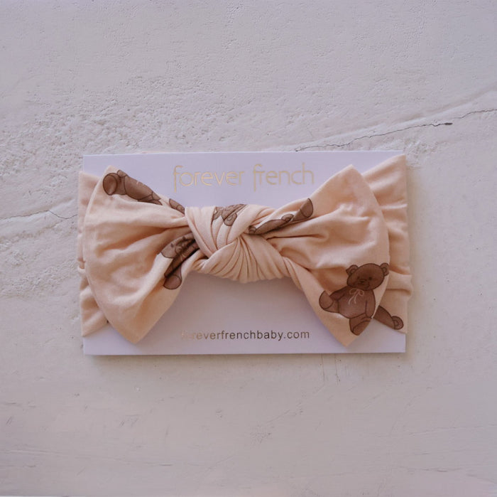 The Bamboo Head Wrap | Lottie by forever french baby, in peach with brown teddy bear prints, is shown on a "forever french" branded card against a light textured background.