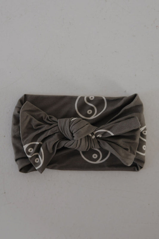 The Bamboo Head Wrap | Sage Yin Yang by forever french baby features a sage fabric with white yin-yang pattern and a twisted knot center, shown on a light textured surface. Adds cute style to any outfit.