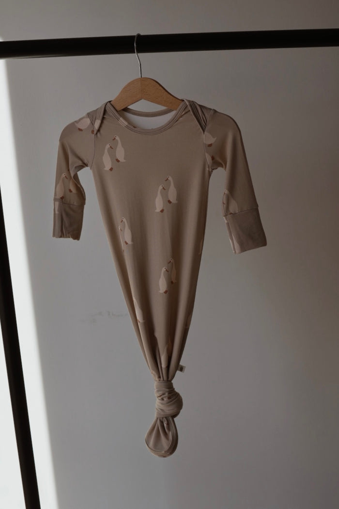 The Bamboo Knotted Gown | Silly Goose by forever french baby is a beige, hypoallergenic bamboo baby gown with long sleeves and a knotted bottom featuring a playful penguin print—perfect cozy wear for your newborn.