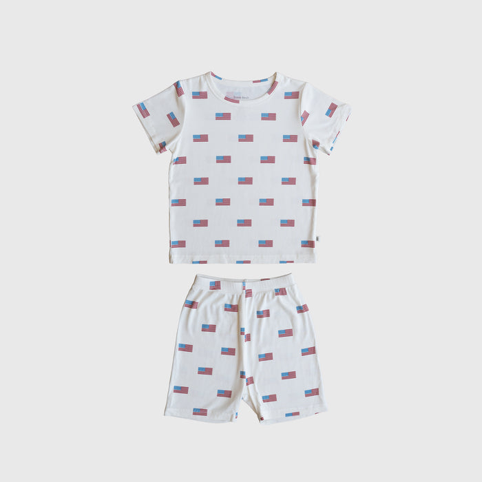 The Bamboo Short Set | Americana Ribbed by forever french baby is a ribbed bamboo short-sleeve pajama set with a white base and red/blue rectangular pattern, including a t-shirt and matching shorts, shown laid flat on white.