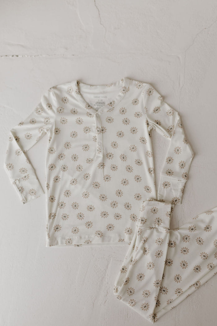 The "Bamboo Two Piece Pajamas | Daisy Fields" by forever french baby is a white long-sleeve set with a buttoned collar, laid flat on a light surface. Made from breathable fabric, these pajamas feature small muted floral designs for ultimate comfort and elegance.