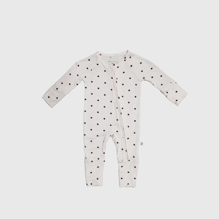 The Bamboo Zip Pajamas | Annie by forever french baby is a white onesie with long sleeves and legs, black polka dots, and an angled zipper, crafted from breathable fabric for all-night comfort.