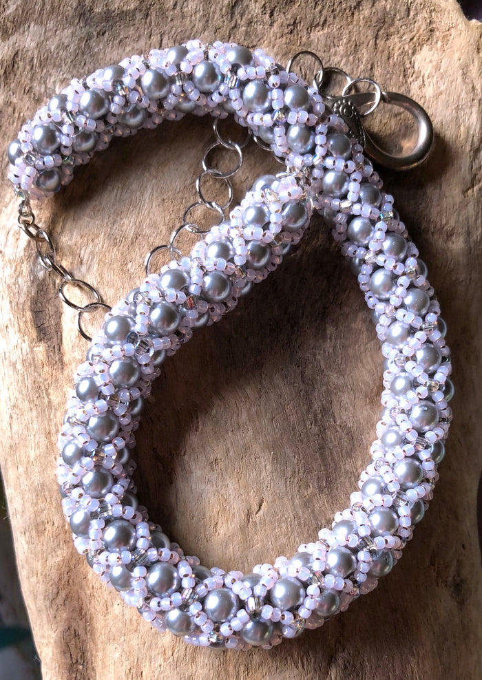 Subtle. This necklace highlights silver Swarovski glass pearls wrapped in a pale pink seed bead netting. It  can be worn from 18 1/4" to 22 1/4".