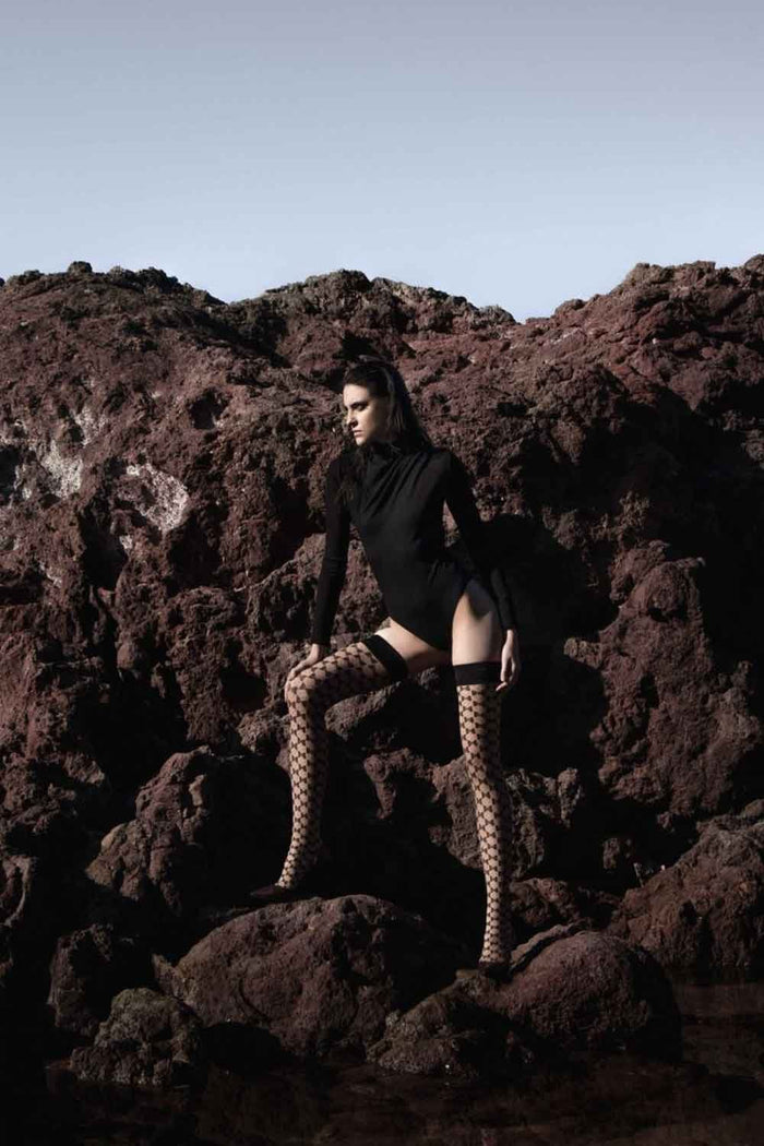 Person in black outfit and  Bellarix hold ups standing on rocky terrain