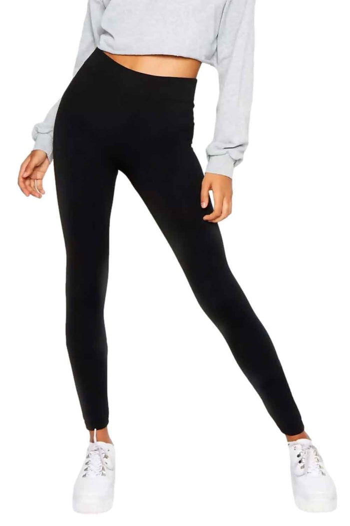 Model wearing black fleece lined leggings with a light grey sweatshirt and white sneakers on a white background
