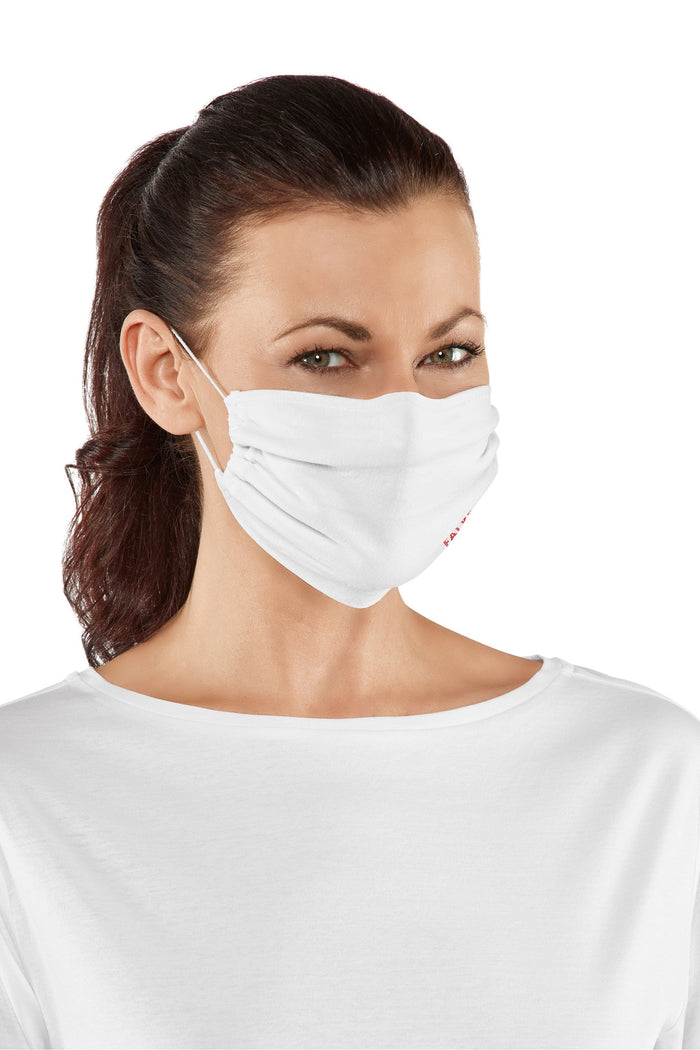 Woman wearing a white face mask against a white background
