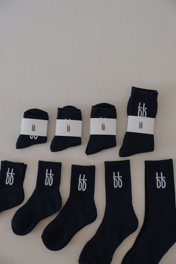 Five pairs of navy ff Crew Socks by forever french baby are displayed in a row; three pairs are wrapped in white labels with a "bb" logo, while two kids’ socks show the same logo on the cuffs.