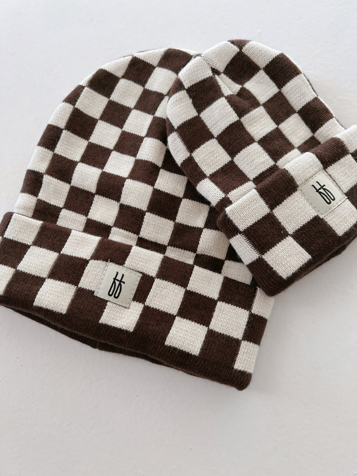 Two Coffee & Cream Checkerboard knit beanies with a folded cuff, each bearing a small, minimalist logo tag at the cuff's edge, are laid out on a white background. With their classic ribbed design and subtle branding, these Forever French Baby ff Knit Beanies are effortlessly stylish.