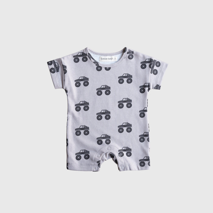 The forever french baby French Terry Romper | Monster Truck is a light gray, short-sleeve romper featuring a black monster truck print, providing breathable comfort for babies and shown flat on a white background.
