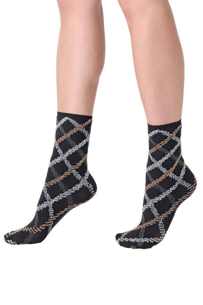 Black patterned tartan socks worn by a person on a white background