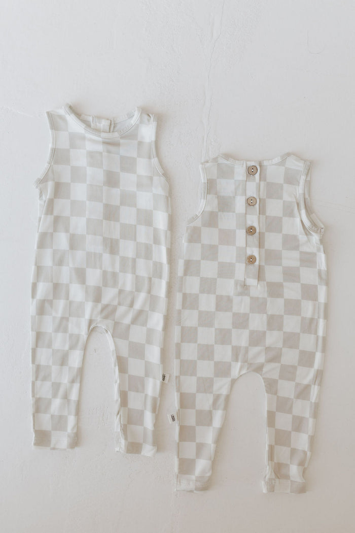 Two "Harem Bamboo Rompers | Checkerboard" by forever french baby, crafted from hypoallergenic bamboo, are displayed front and back. Shown on a light surface in beige and white checkers, they feature buttons and highlight breathable comfort.