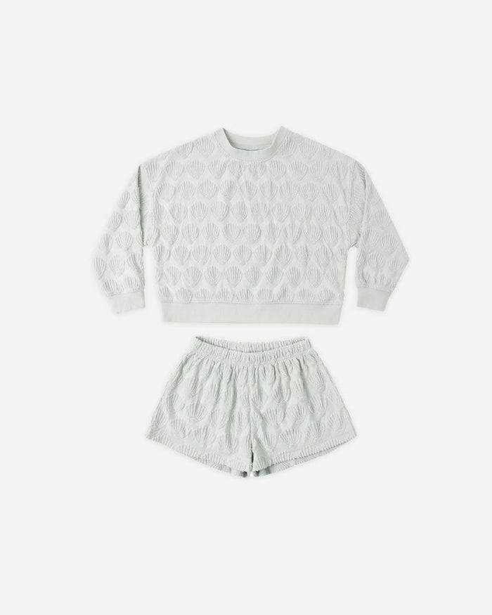 The Karli Set by Rylee + Cru, shown on a plain white background, features a light gray terry cloth sweatshirt and matching shorts with a raised shell pattern that evokes a relaxed coastal vibe.