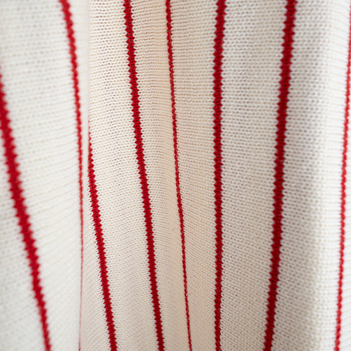 Close-up of the forever french baby Knit Ruffle Romper | Picnic Pinstripe, featuring soft white 100% cotton knit with red vertical stripes. The texture and pattern highlight its comfort and quality—perfect for stylish little ones.