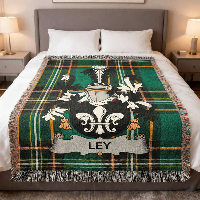 Ley family crest woven blanket laid out on a bed.