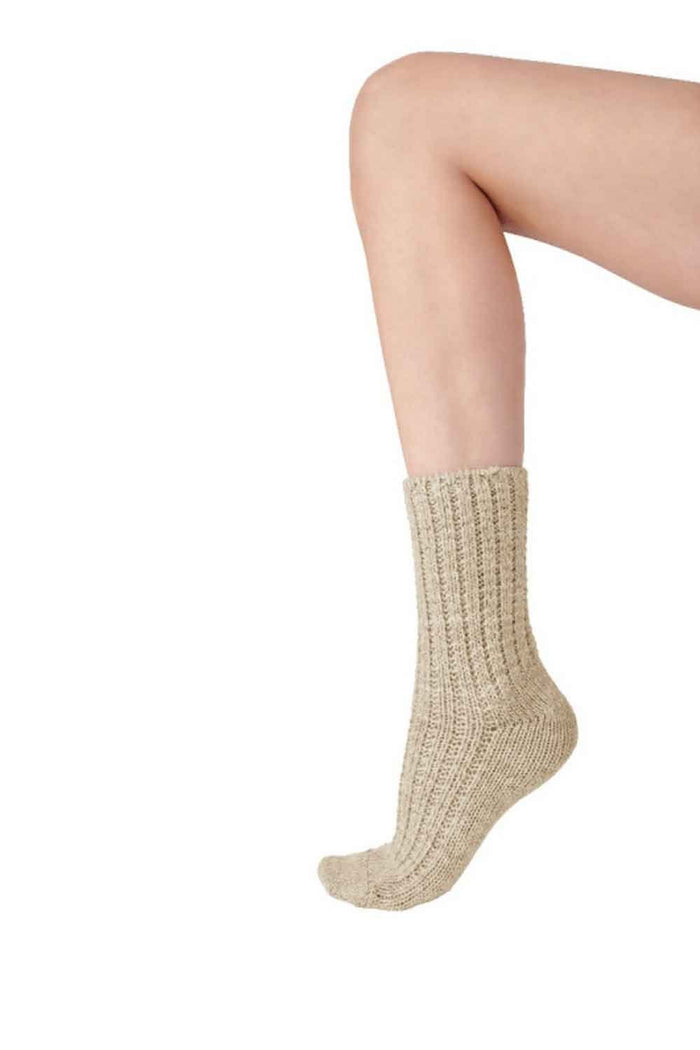 Oatmeal coloured knitted socks worn by a person on a white background
