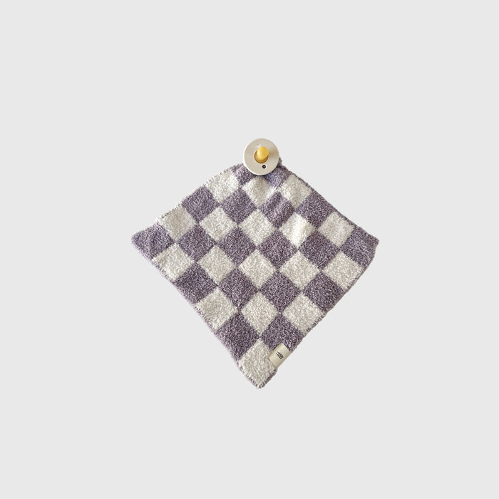 The Lovey | Grape Soda by forever french baby, a purple and white checkered microfiber blanket, is laid flat on a light gray background with a beige pacifier resting on one corner.
