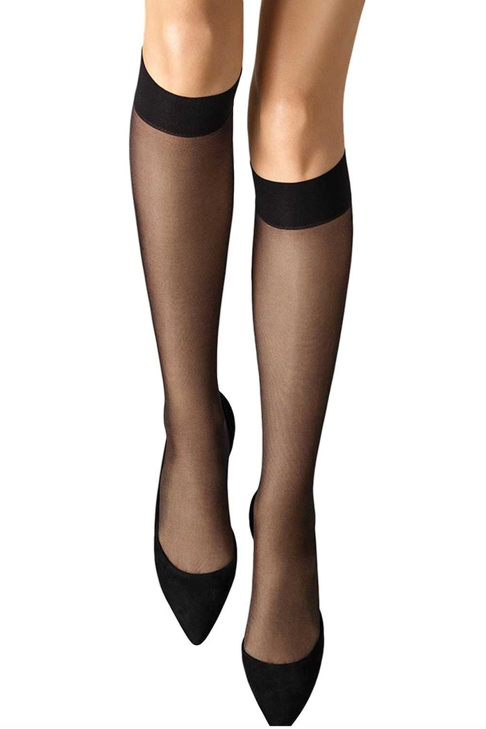 Black sheer knee highs worn with black shoes on a white background