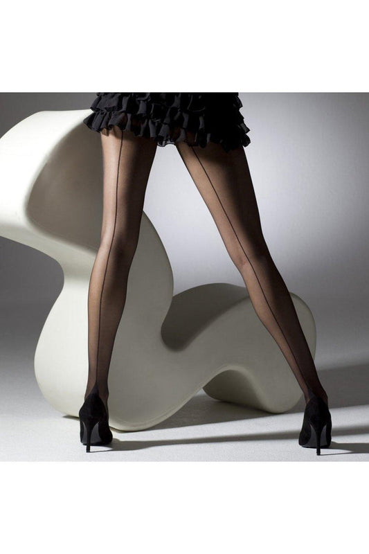 Model wearing sheer black seamed tights  and high heels near  a white chair.
