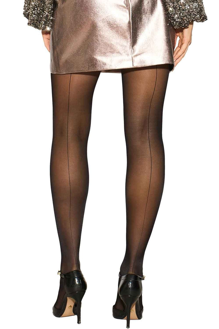 Black back seamed tights worn with a metallic skirt and black shoes on a white background