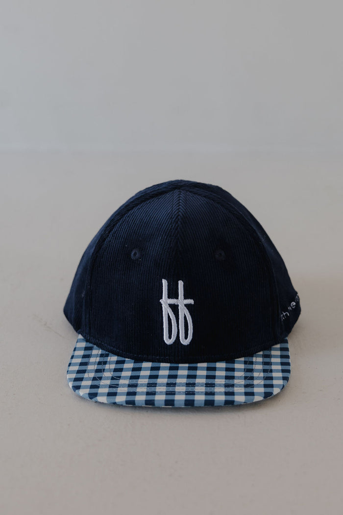 The Snapback | Blue Corduroy ff by forever french baby features a navy blue corduroy design, white embroidered “ff” logo on the front, and a blue-and-white checkered brim—showcasing classic Forever French Baby style.