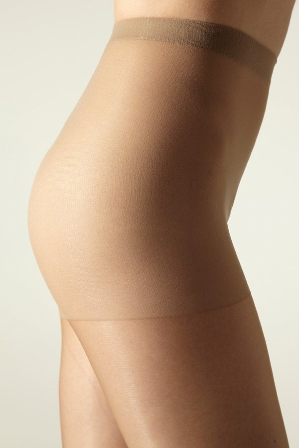 Close-up of a model wearing  beige tights against a neutral background