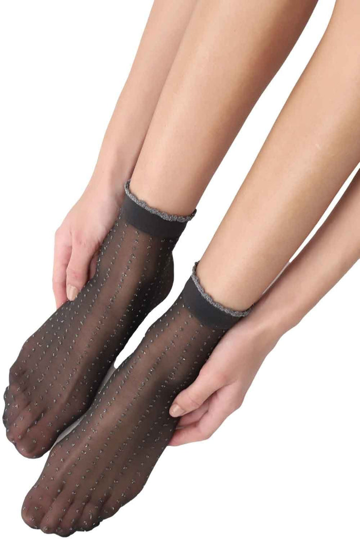 Black/gold glitter dot socks worn by a person on a white background