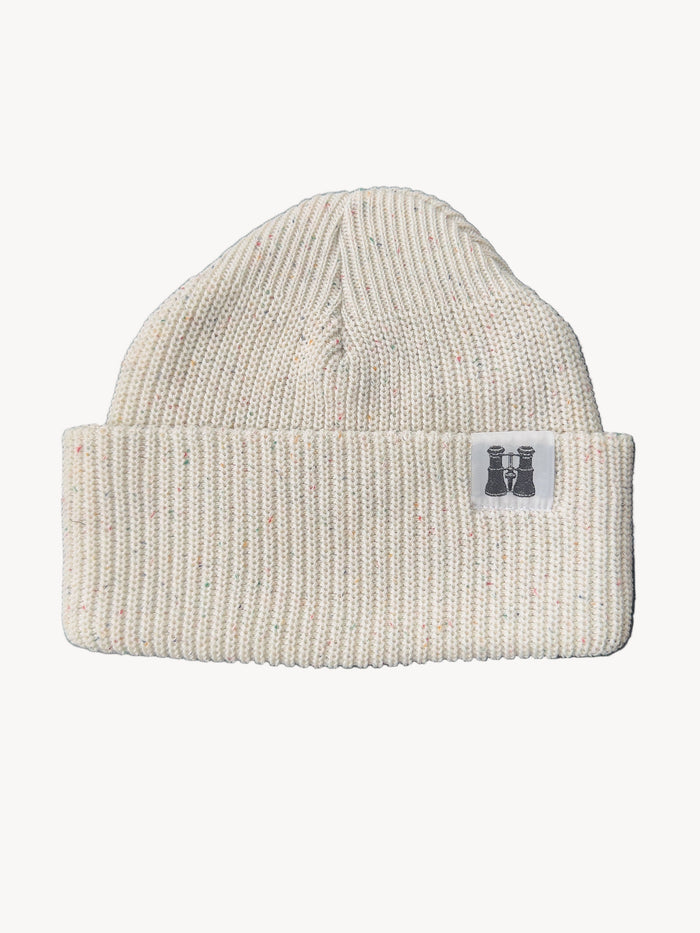 Off White specked knit beanie with a logo tag on a dark textured surface