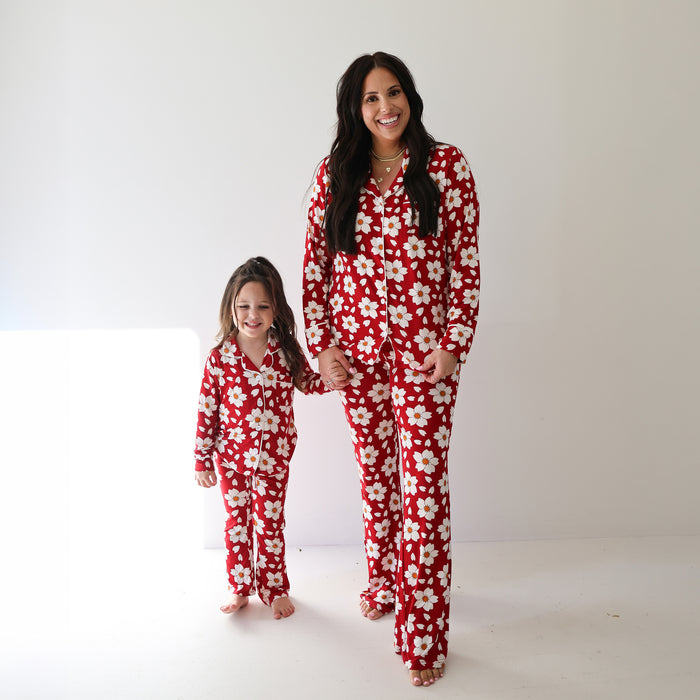 A woman and a young girl stand barefoot, holding hands and smiling, both wearing matching forever french baby Women's Bamboo Button Up Lounge Sets in the Cherry Blossoms print, posing against a plain white background.